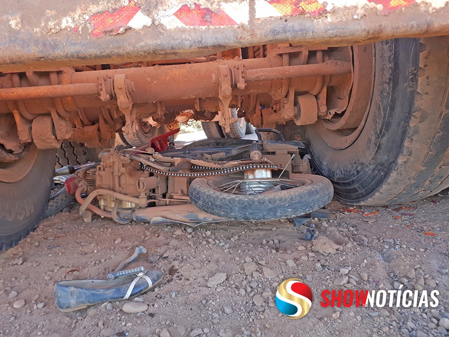 Mulher choca-se com moto contra rodado traseiro de reboque de tora e sai ilesa do acidente.